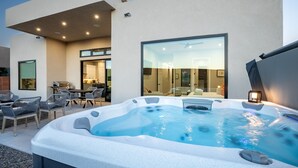 A modern outdoor hot tub area with seating and a glass-enclosed room in the background. - Desert Dreaming 2 Bedroom Home by RedAwning (Washington)