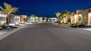 A well-lit street lined with modern buildings, palm trees, and a clear night sky. - Desert Dreaming 2 Bedroom Home by RedAwning (Washington)