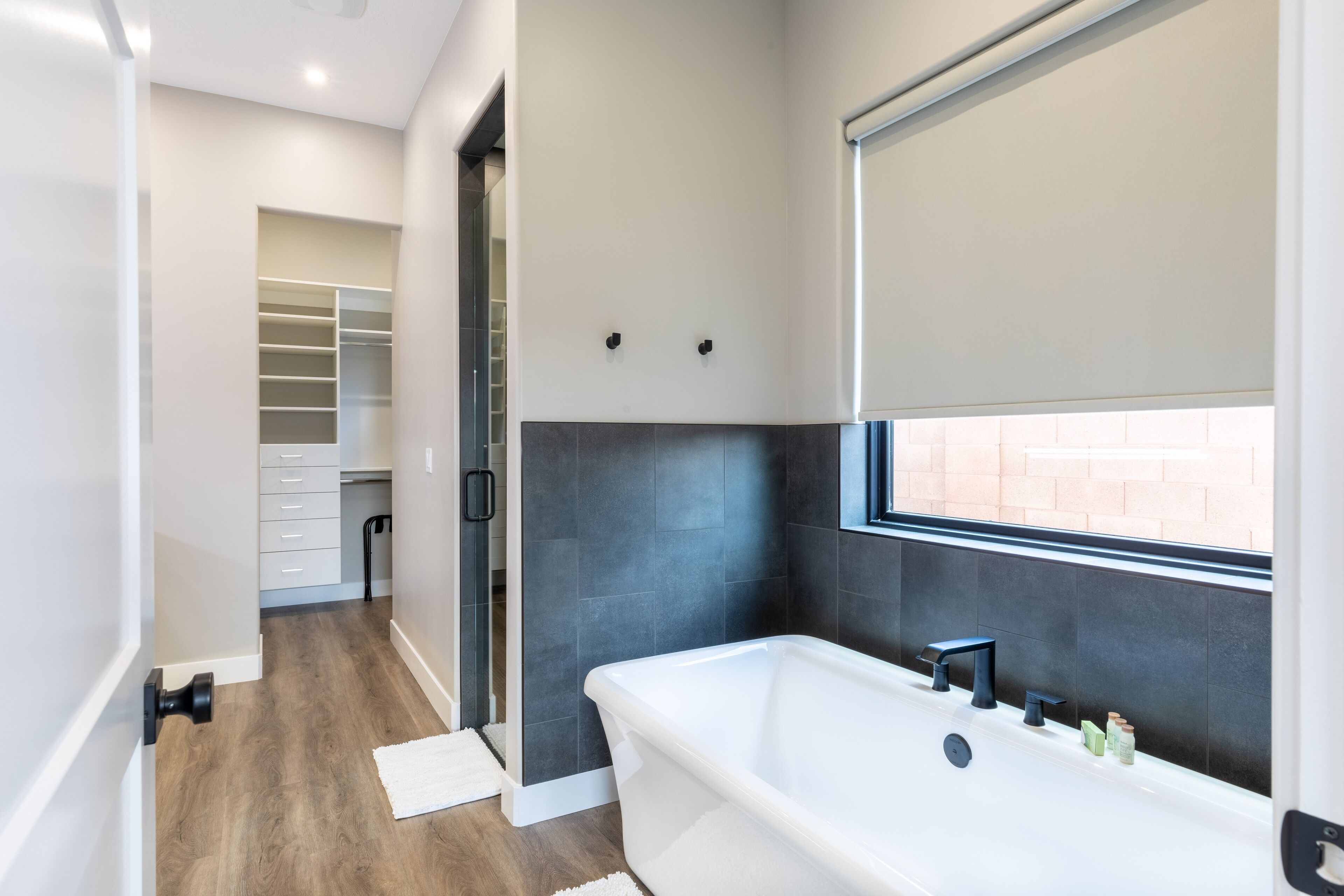Un bagno moderno con una vasca da bagno indipendente, una doccia a filo pavimento e un'ampia finestra che garantisce luce naturale.