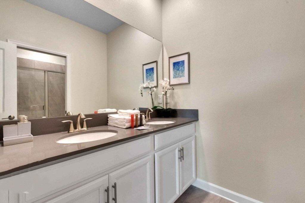 A bathroom with two sinks, a large mirror, and a cabinet.