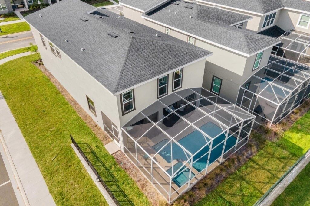 Ein modernes, zweistöckiges Haus mit einem großen, überdachten Schwimmbad und einem gepflegten Rasen.