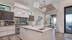 Een moderne keuken met een groot eiland, roestvrijstalen apparatuur en een decoratieve spatwand.