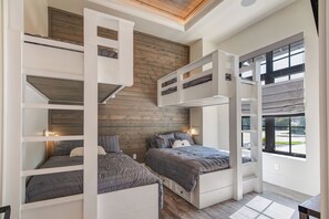 Ein modernes Schlafzimmer mit Stockbetten, einer Holzwand und einem großen Fenster.