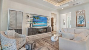 Een moderne woonkamer met een flatscreen televisie, een open haard en een grote witte bank.