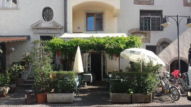 An outdoor café with potted plants, a white umbrella, and bicycles parked nearby. - Argentieri Guesthouse (Bolzano)