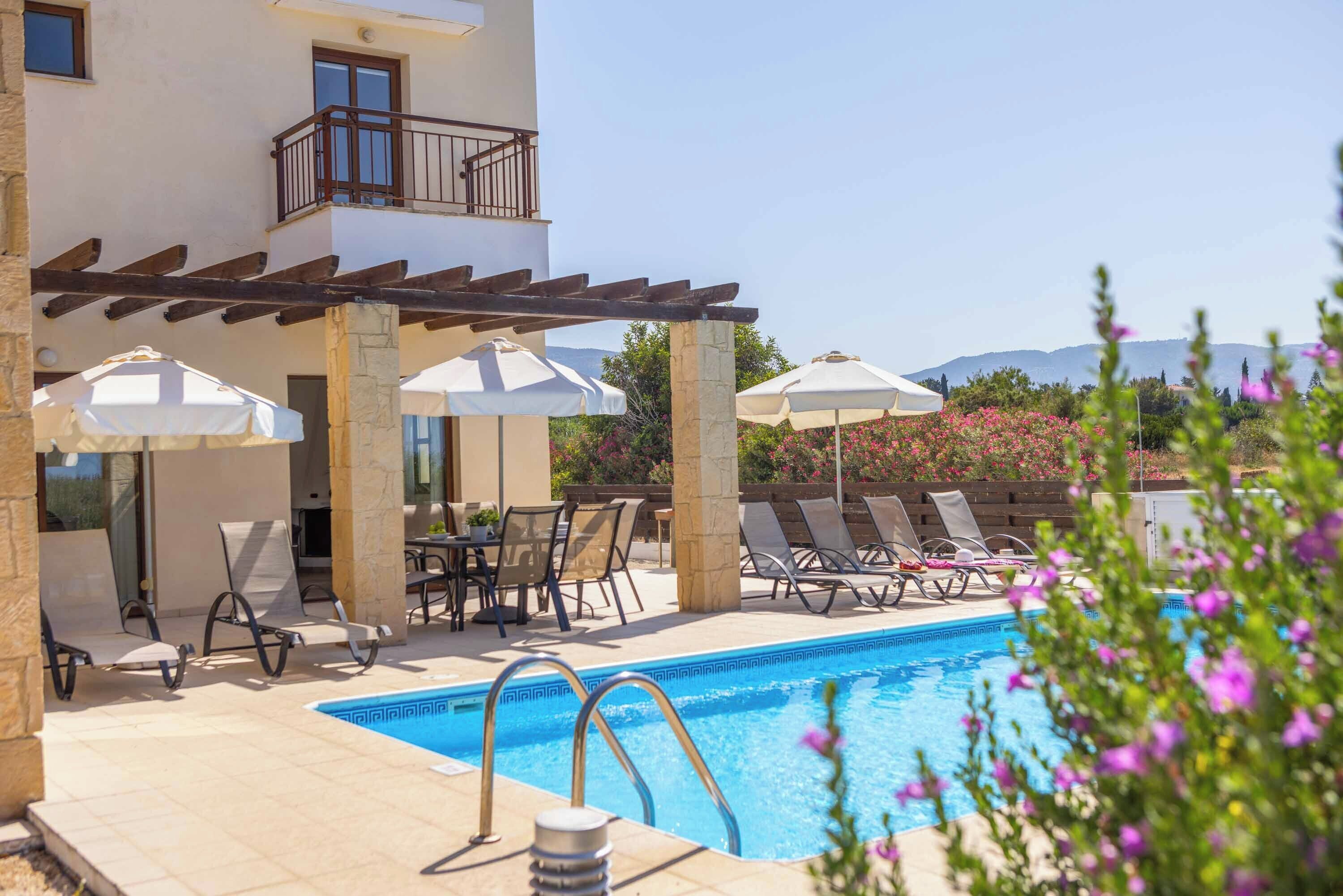 A poolside area with lounge chairs, umbrellas, and a pool.