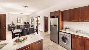 Una cocina moderna con armarios de madera, un refrigerador de acero inoxidable y una lavadora integrada.