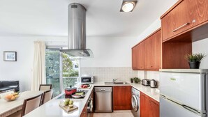 Une cuisine moderne avec des meubles en bois, des appareils électroménagers en acier inoxydable et un îlot central agrémenté de fruits.