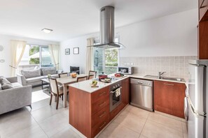 A modern kitchen with a central island, stainless steel appliances, and a dining area with a sofa and chairs.