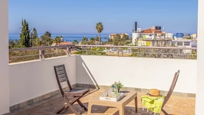 A balcony with a view of the sea, a table with a hat, and two chairs. - Coral Olympus Poseidon (Peyia)
