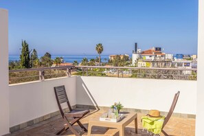 A balcony with a view of the sea, a table with a hat, and two chairs. - Coral Olympus Poseidon (Peyia)