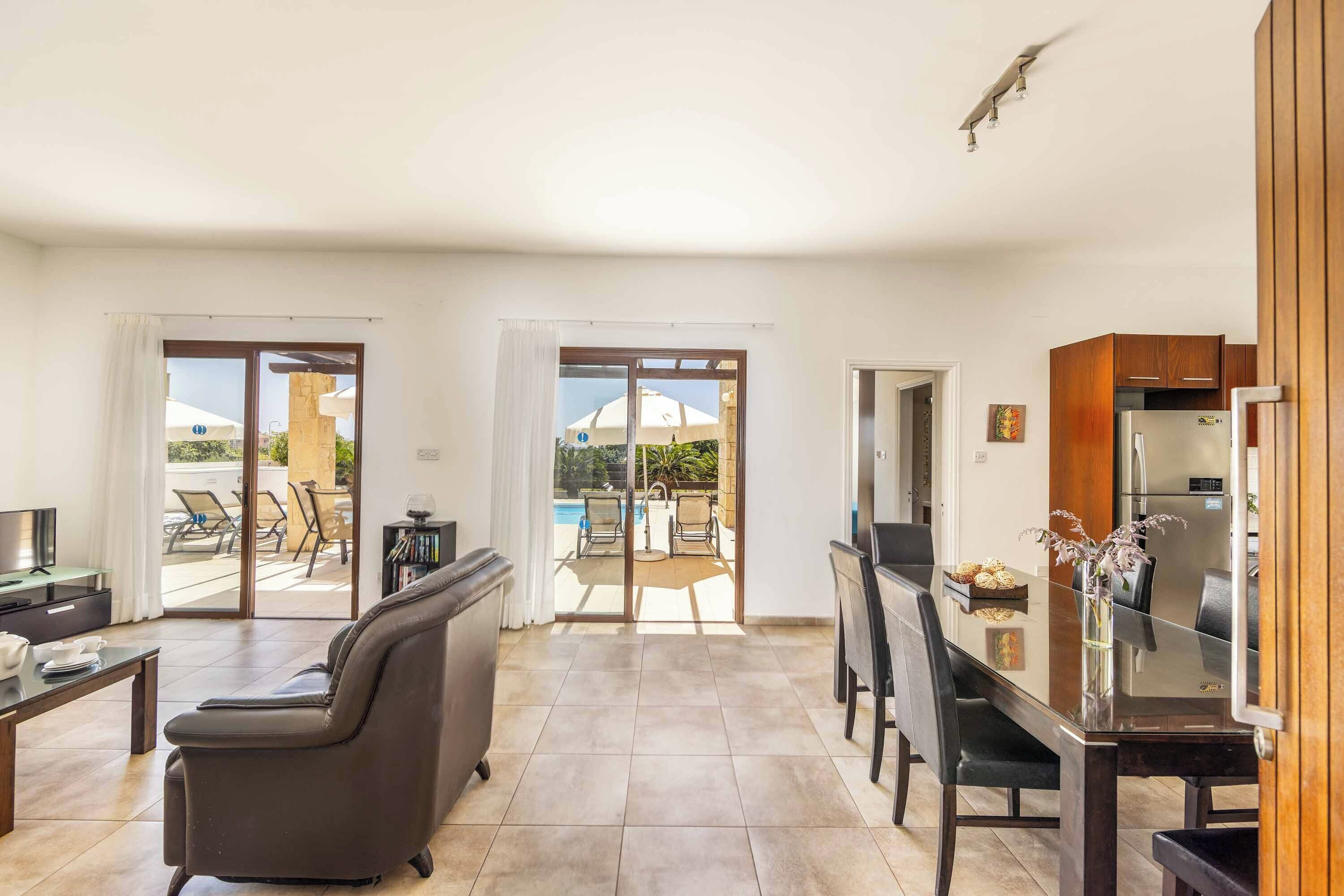 Una sala de estar moderna con un sofá, una mesa de comedor y una zona de cocina con refrigerador.