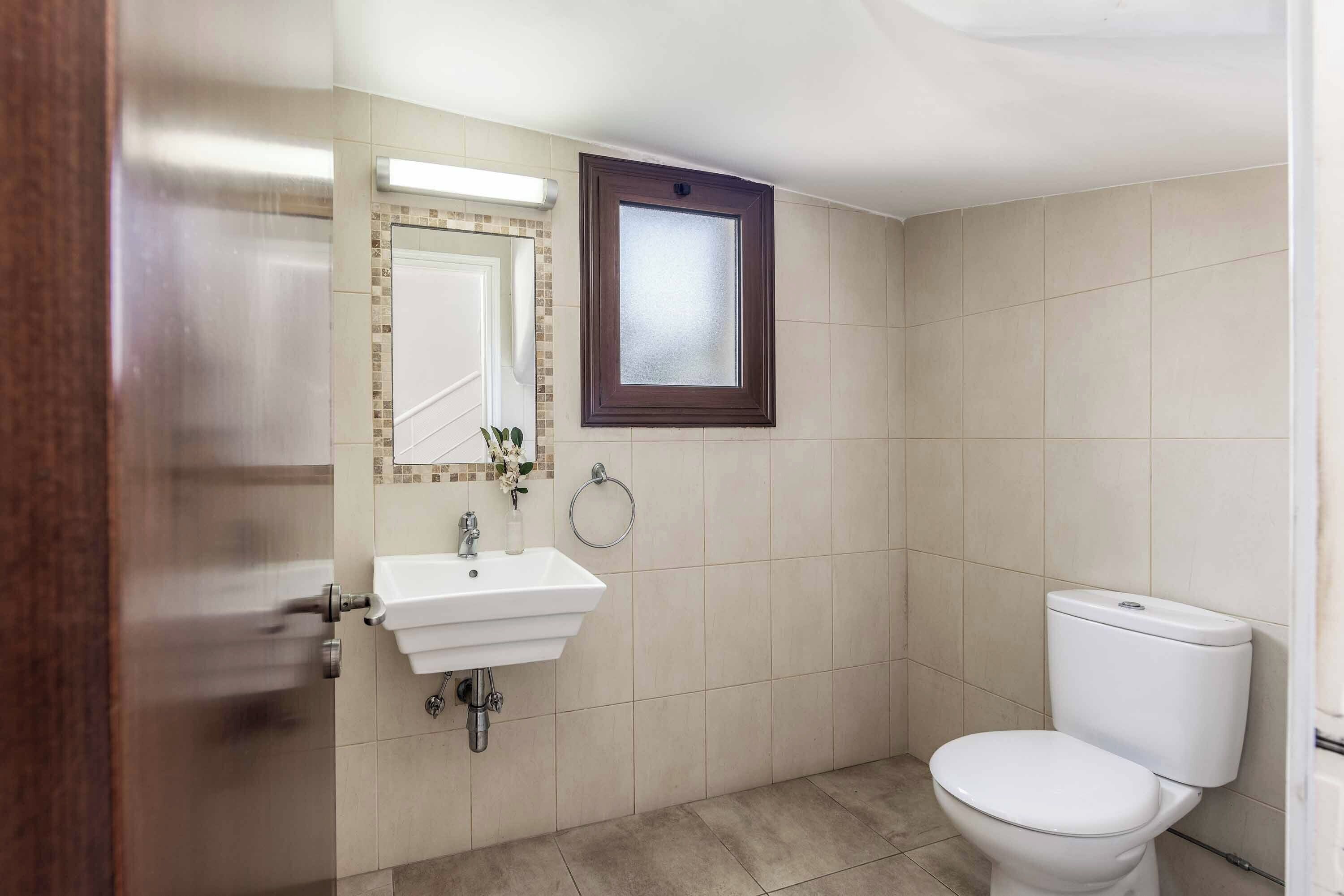 A bathroom with a white sink, a mirror, and a toilet.