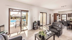 A spacious living area with a pool view, a dining area, and a kitchen.