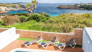 Zona de piscina con sillones de descanso y vista al mar.