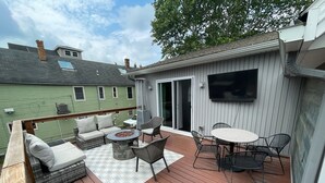 Une terrasse dotée de mobilier d’extérieur, d’un foyer et d’un téléviseur fixé au mur.