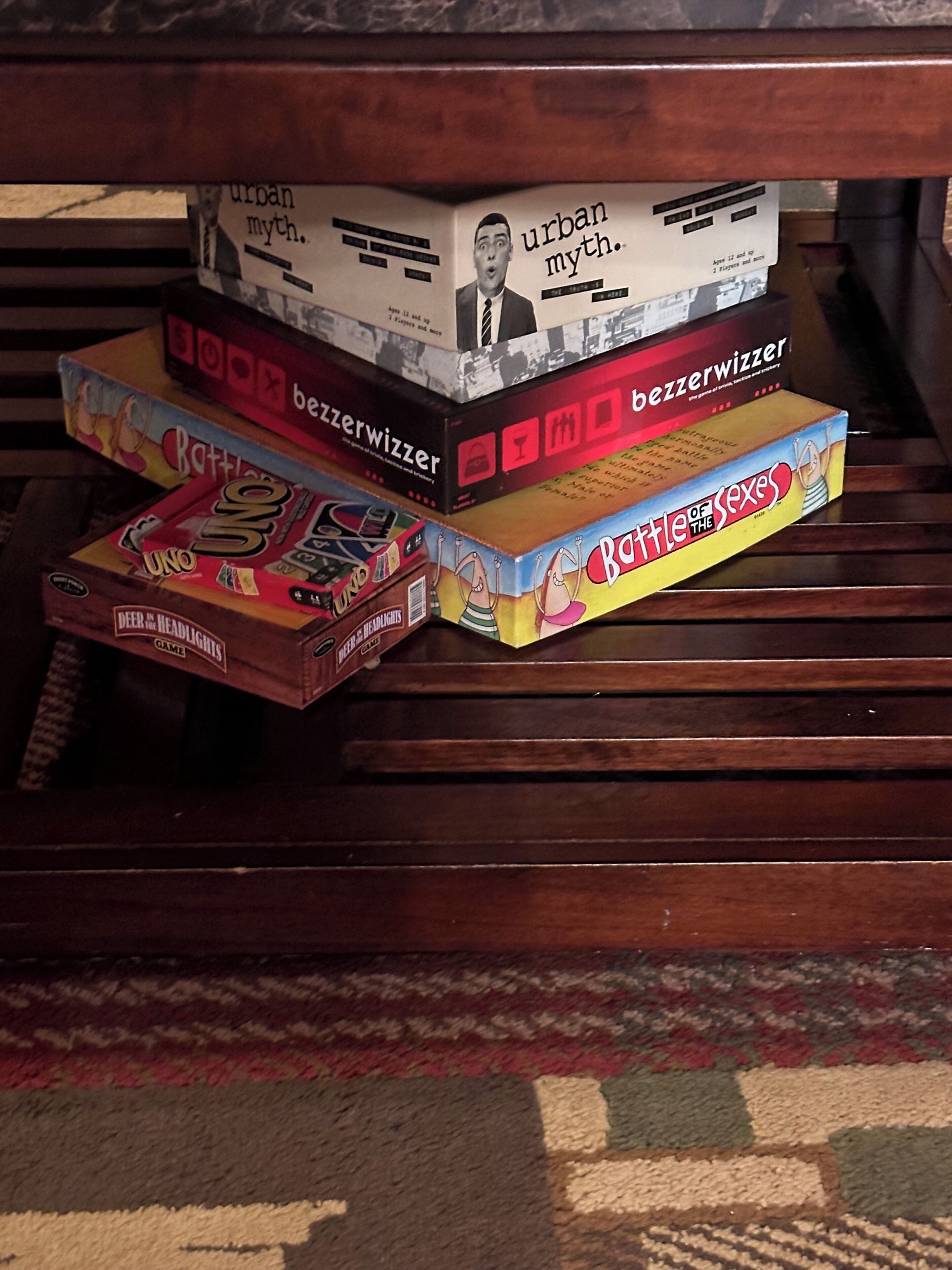 A stack of board games on a wooden surface.