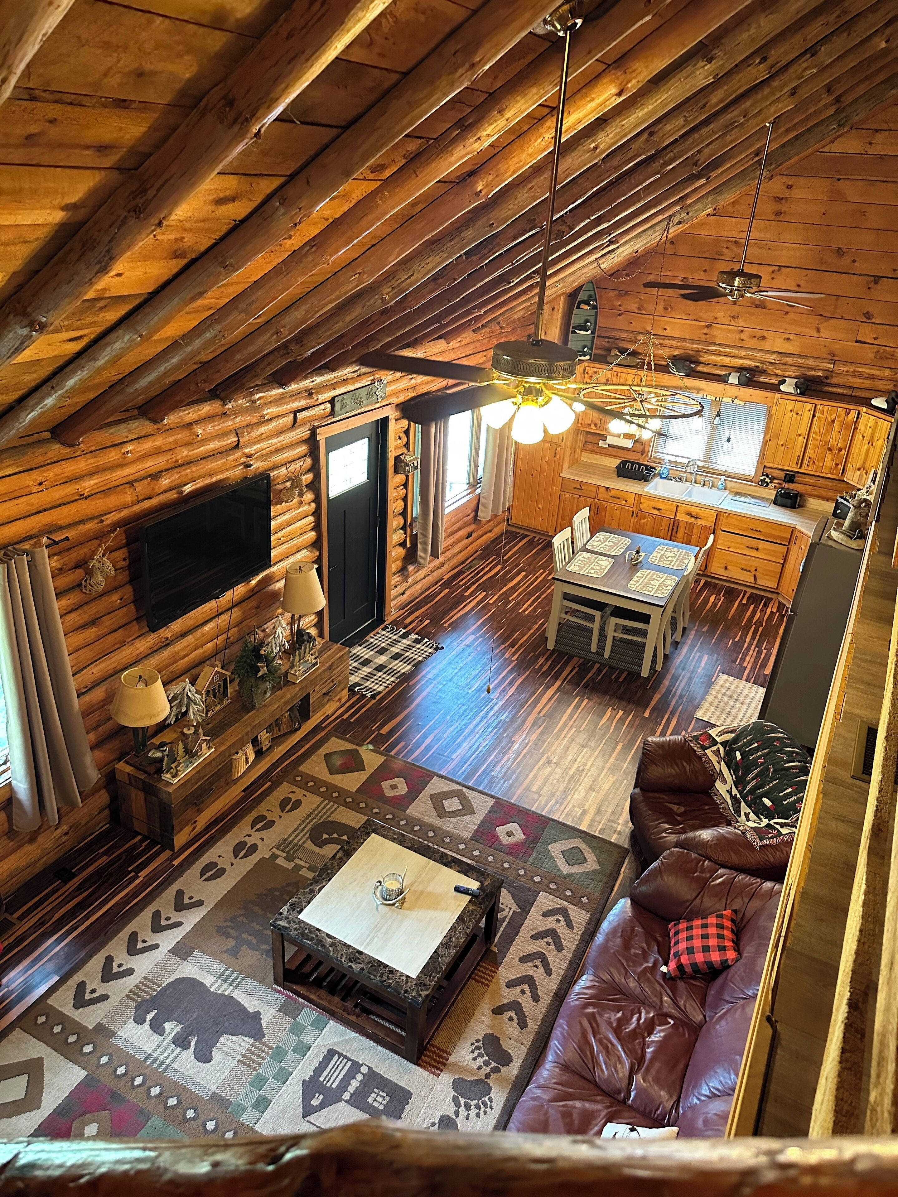 A log cabin interior with a dining area, kitchen, and seating space.