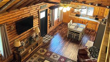 A log cabin interior with a dining area, kitchen, and seating space.