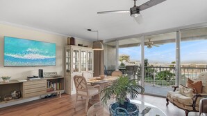 A spacious living room with a large window, a dining area, and a balcony with a view of the landscape. - 1BR Coastal Condo + 3 Pools & Private Beach Access | Magnolia House 107 (Destin)