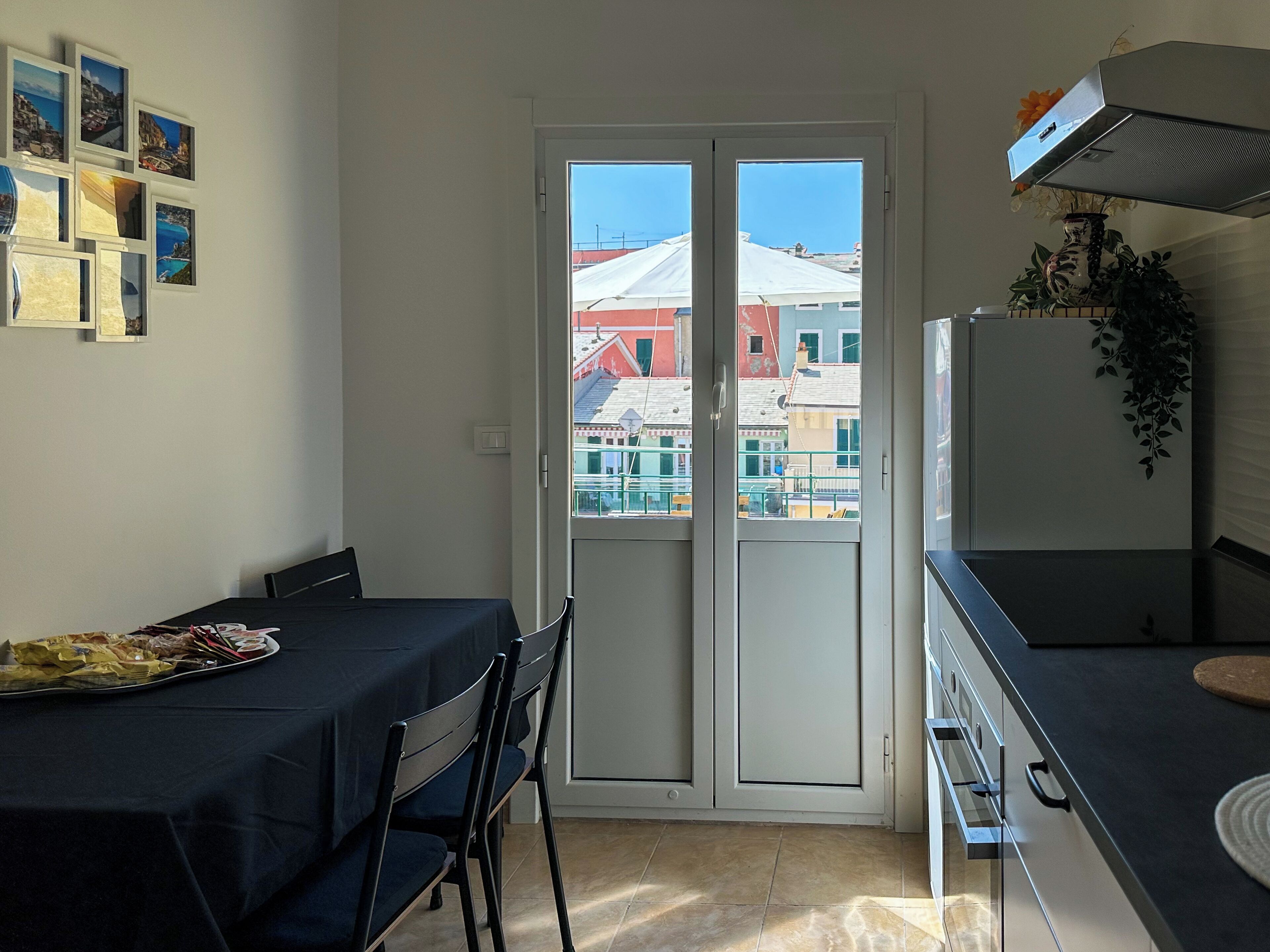 Cocina compacta con comedor, puerta corrediza de vidrio que da a un balcón exterior y un refrigerador pequeño.