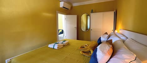 Une chambre d’hôtel comprenant un lit, une table de chevet, un miroir et une porte donnant sur une autre pièce.
