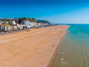 A wide beach with a clear view of the ocean and a town in the background.