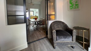 A modern interior with a dining area, a wicker chair, and a wall-mounted light fixture. - Sea Haven  Stylish Beach Oasis - Pass the Keys (Hastings)