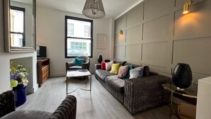 A modern living room with a sofa, armchairs, a coffee table, and a TV. - Sea Haven  Stylish Beach Oasis - Pass the Keys (Hastings)