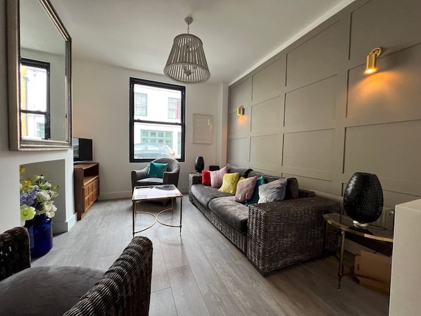 A modern living room with a sofa, armchairs, a coffee table, and a TV.