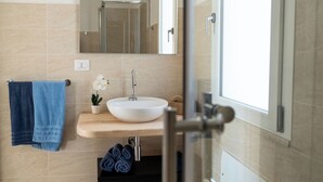 A modern bathroom with a large mirror, a white sink, and a shower.