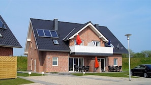 Situated in a well-maintained area, this two-story building features a balcony with outdoor seating and solar panels on the roof.