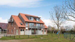 Un immeuble résidentiel de deux étages, doté d’un toit en pente, de grandes fenêtres et d’un balcon.