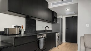 Eine moderne Küche mit dunklen Schränken, einem Edelstahl-Kühlschrank, einem Einbauofen und einer Mikrowelle.