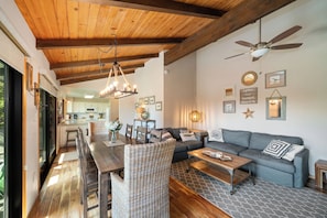 Ein geräumiger Wohnbereich mit Holzboden, Deckenventilator, Esstisch mit Stühlen, einer Couch und einem Couchtisch.