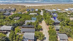 Luchtbeeld van een kustgebied met woningen, een strand en een markeerde locatie.