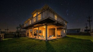 Ein zweistöckiges Haus mit einem Balkon, einer überdachten Terrasse und einem gepflegten Rasen.