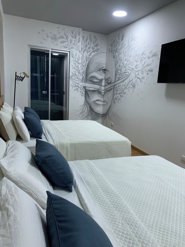 Une chambre avec deux lits, du linge de lit blanc et une grande fresque murale.