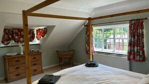 A bedroom with a four-poster bed, a wooden dresser, a chair, and a window with curtains. - Charming Group Stay – Peaceful Retreat near London (Bexley,)