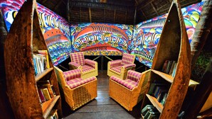 A room with a unique ceiling design, wicker furniture, and bookshelves. - Simply Saadani Camp (Mkwaja)