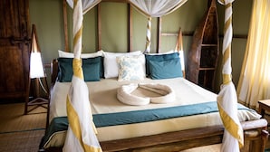 A bed with a canopy, pillows, and a bedside table. - Simply Saadani Camp (Mkwaja)