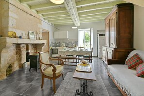 Un amplio salón con sofá, una mesa de comedor con sillas, una chimenea y una cocina al fondo.