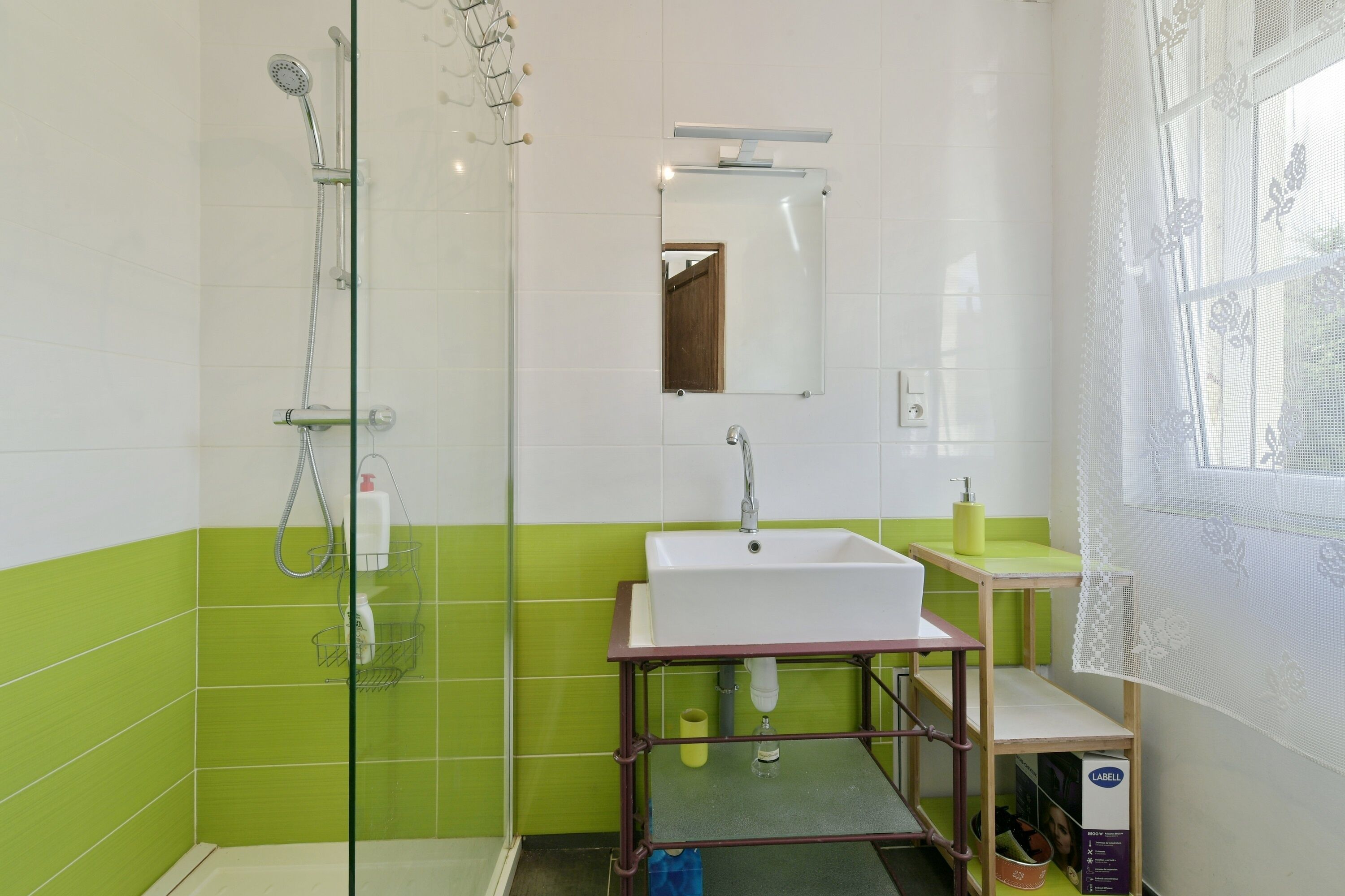 Une salle de bain avec une douche à parois de verre, un lavabo blanc et un miroir au-dessus.