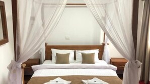Una cama bien hecha con cabecera de madera, ropa de cama blanca y un detalle en marrón.