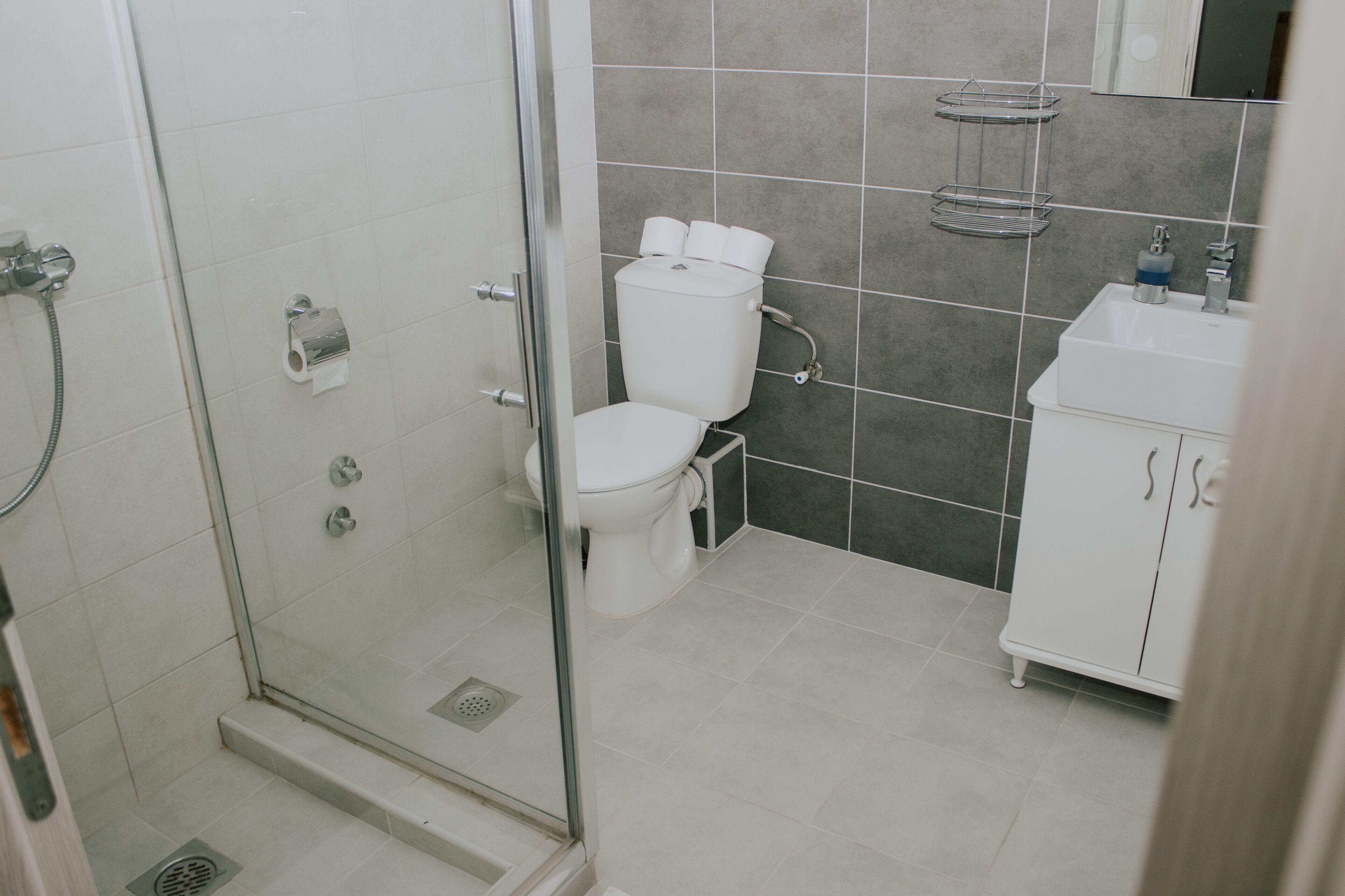 Ein Badezimmer mit Duschkabine, Toilette, Waschbecken und Schrank.