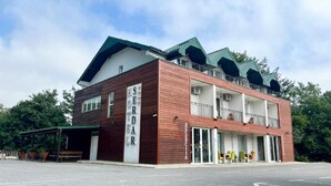 Un edificio de dos pisos con fachada de madera, techo verde y un balc ón con mesas al aire libre.