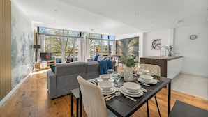 A modern living room with a dining area, large windows, and a kitchen area. - Modern Luxe Living in Lincoln - Flat 3 (Lincolnshire)