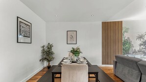 A dining area with a table set for four, a grey sofa, and two framed artworks on the walls. - Modern Luxe Living in Lincoln - Flat 3 (Lincolnshire)