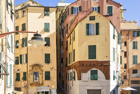 A narrow street with buildings featuring balconies and shutters.