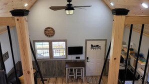Una cocina acogedora con vigas de madera, un ventilador de techo, un reloj, un cartel de bienvenida y un televisor.